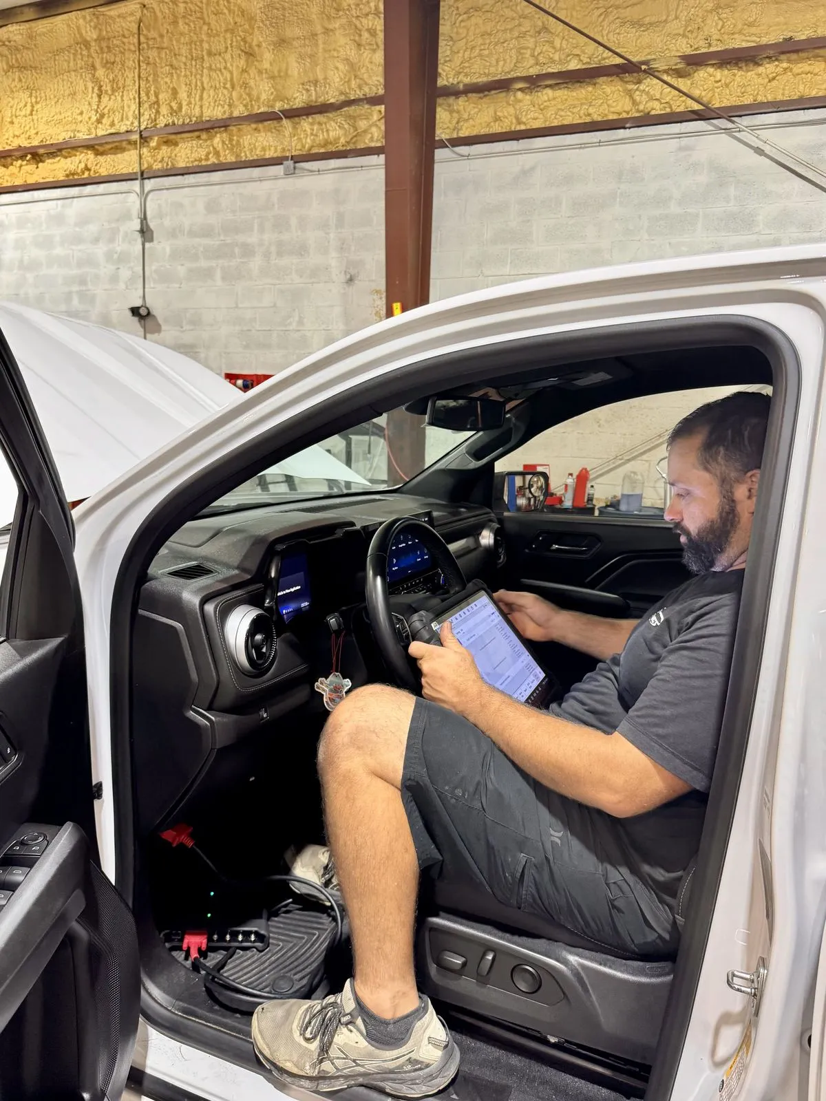 Technician running computer diagnostics with a professional scan tool inside a late-model GM truck